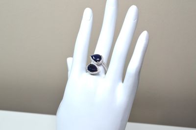 une main sur laquelle est passée une bague sertie d'une pierre bleue