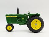 a green toy tractor with yellow wheels on a white surface