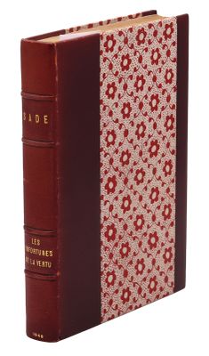 an old book with a red cover sitting on top of a white surface