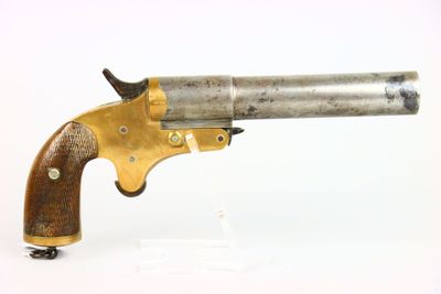 gros plan d'un pistolet avec un manche en bois sur une surface blanche