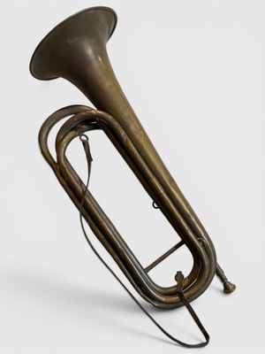 un vieux tuba en laiton est posé sur une surface blanche