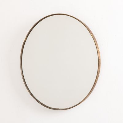 un miroir rond accroché au mur, à côté d'un mur blanc