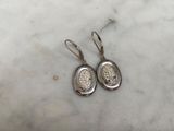 a pair of silver earrings on a marble surface