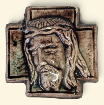 une croix en céramique sur laquelle est représenté le visage de Jésus