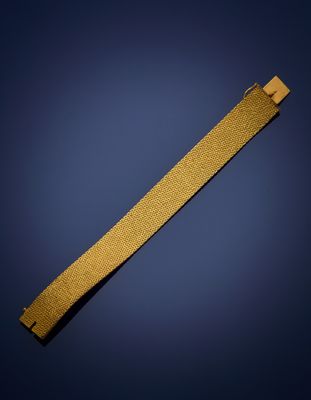 un gros plan d'un bracelet doré sur fond bleu