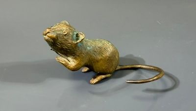 statue d'une souris assise sur ses pattes arrière sur une surface grise