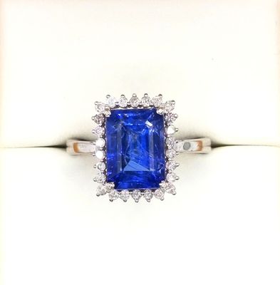 a close up of a blue sapphire and diamond ring on a white surface