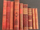 several old books are lined up in a row on a table