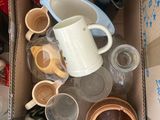une boîte en carton remplie de tasses et de soucoupes, posée par terre