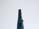 a blue vase sitting on top of a white table next to a white wall