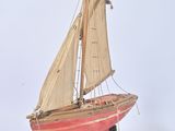wooden model of a sailboat on a stand on a white surface