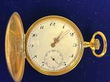 une image représentant une montre de poche en or posée sur une surface bleue