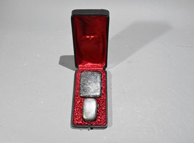 une petite boîte rouge contenant deux pierres argentées