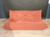 un canapé-futon orange sur lequel est posé un oreiller