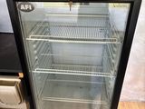 a glass door refrigerator that is open on a wooden floor