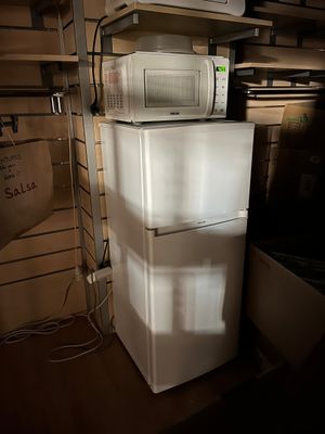un micro-ondes posé sur un réfrigérateur dans une pièce