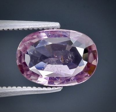 a close up of a pink sapphire being held by a pair of pliers