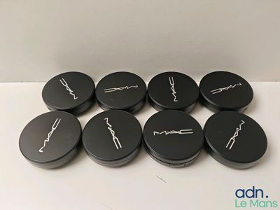 six couvercles de macarons noirs avec une inscription blanche, posés sur une surface blanche