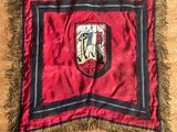 un vieux drapeau rouge et noir orné d'un blason