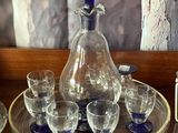 bottles and glasses on a tray on a table in front of a painting