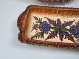 two decorative dishes sitting on a table next to each other