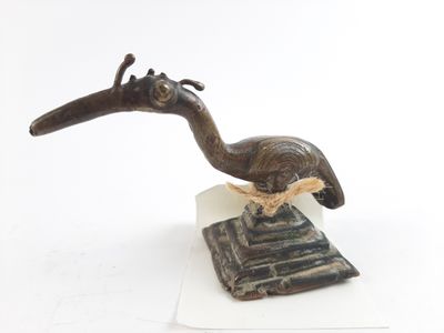 sculpture of a bird on a stand on a white surface