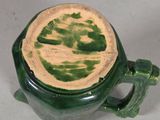 a green mug with a lid that has a leaf on it