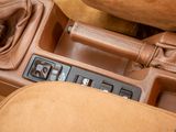 a car dashboard with a brown leather gear box and a brown bag