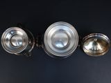 three antique silverplated teapots on a black background