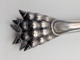 a silver spoon with spikes on it on a white surface