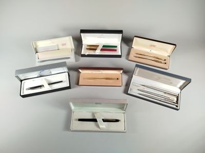 six different pens and a pen in a box on a table