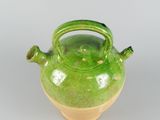a green tea pot with a handle on a white surface