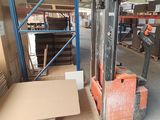 un chariot élévateur dans un entrepôt, chargé de nombreuses caisses