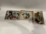 trois boîtes contenant des objets en verre de différentes couleurs