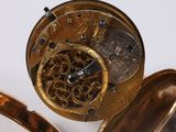 a close up of a gold pocket watch on a white surface