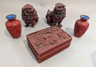 trois vases rouges posés les uns à côté des autres sur une table