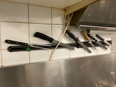 a lot of knives hanging on the wall in the kitchen