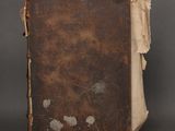 an old book sitting on top of a table next to a gray wall
