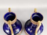 two blue vases with gold handles on a white surface
