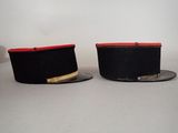 pair of black hats with red trims on top of each other
