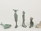 three bronze statues of animals and a bird on a white surface