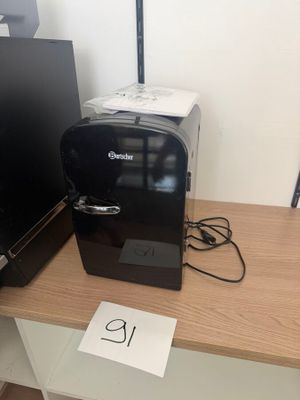 a small coffee maker on a desk next to a computer