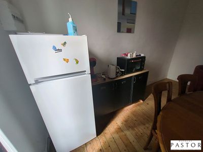 un réfrigérateur dans un coin d'une pièce où se trouvent une table et des chaises