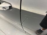 a person standing in front of a car with their reflection in the side mirror