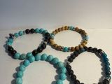 quatre bracelets de couleurs et de tailles différentes posés sur une surface blanche