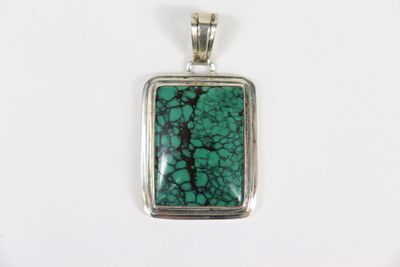 un pendentif en argent orné d'une pierre verte au centre