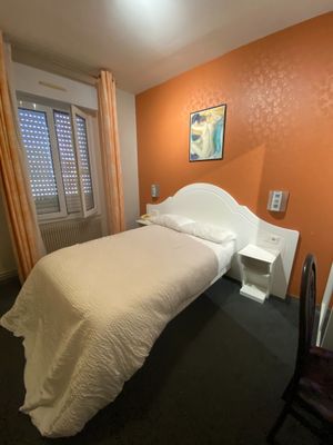 a white bed sitting in a bedroom next to a window
