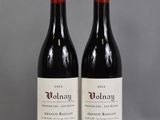 two bottles of red wine sitting on top of a table