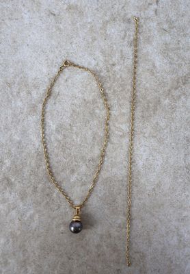 une chaîne en or ornée d'une perle noire et une chaîne en or ornée d'une perle noire