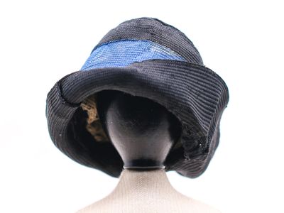 un chapeau noir sur la tête d'un mannequin, orné d'un ruban bleu